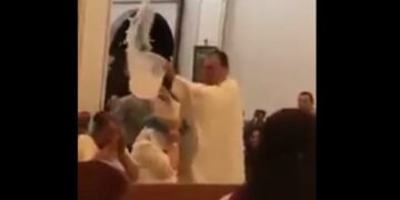 Un sacerdote bañó con un balde lleno de agua bendita a sus fieles