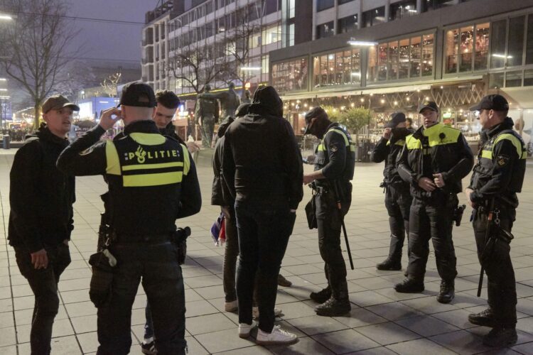 ROTTERDAM, NETHERLANDS - DECEMBER 18: Police officers control a group of football fan on December 18, 2021 in Rotterdam, Netherlands. The authorities advice not to travel to Rotterdam as shoppers flocked to the shopping streets prior to a hard lockdown. The government will announce a hard lockdown closing all non-essential shops from tomorrow morning until at least January 14 2022 in an attempt to fight the Coronavirus pandemic and its Omicron variant. Gatherings of more than two persons in and outside will be prohibited. (Photo by Pierre Crom/Getty Images)