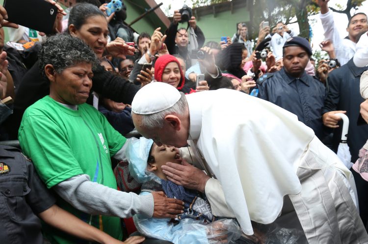 BRA129. RÍO DE JANEIRO (BRASIL), 25/07/2013.- El papa Francisco besa a un niño hoy, jueves 25 de julio de 2013, durante su visita a la favela Varginha en Río de Janeiro (Brasil). El pontífice visitó hoy una favela, donde dijo que "nadie puede permanecer indiferente ante las desigualdades que existen en el mundo". Además, en su visita el complejo de favelas de Manguinhos, en la zona norte de Río de Janeiro, donde viven unas 2.000 personas en casas hechas con cartón y materiales de derribo, pidió a los poderes públicos que trabajen por un mundo más justo y solidario y a los jóvenes que luchen contra la corrupción y la injusticia. EFE/Antonio Lacerda