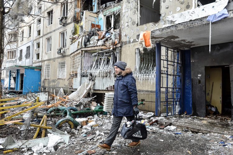A man leaves an apartment building damaged after shelling the day before in Ukraine's second-biggest city of Kharkiv on March 8, 2022. - The number of refugees flooding across Ukraine's borders to escape towns devastated by shelling and air strikes passed two million, in Europe's fastest-growing refugee crisis since World War II, according to the United Nations. (Photo by Sergey BOBOK / AFP)