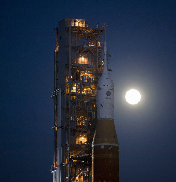 The Moon is seen rising behind NASA’s Space Launch System (SLS) rocket with the Orion spacecraft aboard atop a mobile launcher as it rolls out to Launch Complex 39B for the first time, Thursday, March 17, 2022, at NASA’s Kennedy Space Center in Florida. Ahead of NASA’s Artemis I flight test, the fully stacked and integrated SLS rocket and Orion spacecraft will undergo a wet dress rehearsal at Launch Complex 39B to verify systems and practice countdown procedures for the first launch. Photo Credit: (NASA/Aubrey Gemignani)