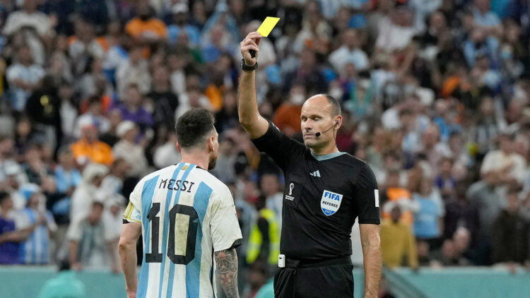 Referee Antonio Mateu shows a yellow card to Argentina's Lionel Messi during the World Cup quarterfinal soccer match between the Netherlands and Argentina, at the Lusail Stadium in Lusail, Qatar, Saturday, Dec. 10, 2022. (AP Photo/Ricardo Mazalan)