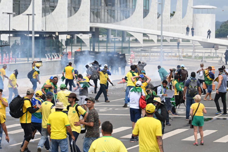 Supporters of Brazilian former President Jair Bolsonaro clash with the police during a demonstration outside the Planalto Palace in Brasilia on January 8, 2023. - Brazilian police used tear gas Sunday to repel hundreds of supporters of far-right ex-president Jair Bolsonaro after they stormed onto Congress grounds one week after President Luis Inacio Lula da Silva's inauguration, an AFP photographer witnessed. (Photo by EVARISTO SA / AFP)