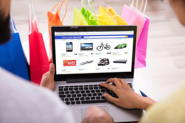 Close-up Of A Couple Shopping Online In Front Of Multi Colored Shopping Bags At Home