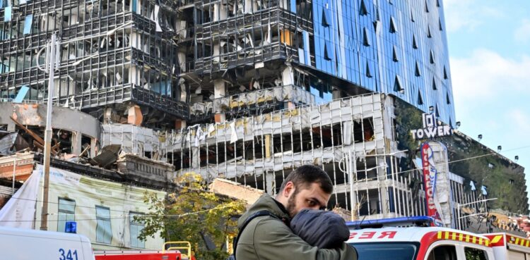 TOPSHOT - People react outside a partially destroyed multistorey office building after several Russian strikes hit the Ukrainian capital of Kyiv on October 10, 2022, amid Russia's invasion of Ukraine. - The head of the Ukrainian military said that Russian forces launched at least 75 missiles at Ukraine on Monday morning, with fatal strikes targeting the capital Kyiv, and cities in the south and west. (Photo by Sergei SUPINSKY / AFP) (Photo by SERGEI SUPINSKY/AFP via Getty Images)