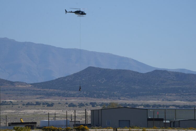 A helicopter carries NASAs Osiris-Rex asteroid sample return craft from the Utah desert, where it landed, to a clean room at Dugway, Utah, on September 24, 2023. The largest sample ever collected from an asteroid in space, and the first for NASA, landed in the Utah desert Sunday after a fiery final descent through Earth's atmosphere, seven years after the mission's launch. Scientists hope the asteroid sample aboard the spacecraft will provide humanity with a better understanding on the formation of our solar system and how Earth became habitable. (Photo by GEORGE FREY / AFP)