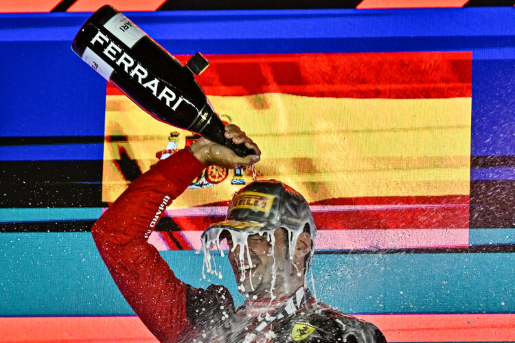 Ferrari's Spanish driver Carlos Sainz Jr pours champagne on himself as he celebrates on the podium after winning the Singapore Formula One Grand Prix night race at the Marina Bay Street Circuit in Singapore on September 17, 2023. (Photo by Lillian SUWANRUMPHA / AFP)