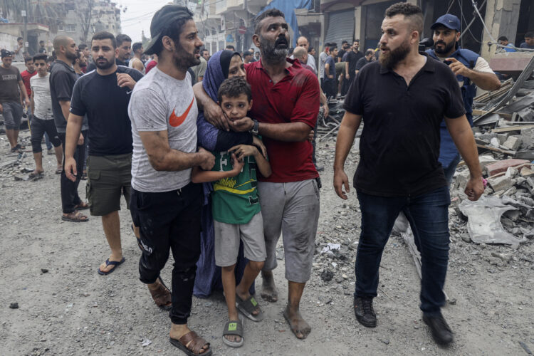 Members of a Palestinian family comfort a child in shock as they leave their destroyed home following Israeli airstrikes on Gaza City on October 9, 2023. Stunned by the unprecedented assault on its territory, a grieving Israel has counted over 700 dead and launched a withering barrage of strikes on Gaza that have raised the death toll there to 493 according to Palestinian officials. (Photo by Eyad AL-BABA / AFP)