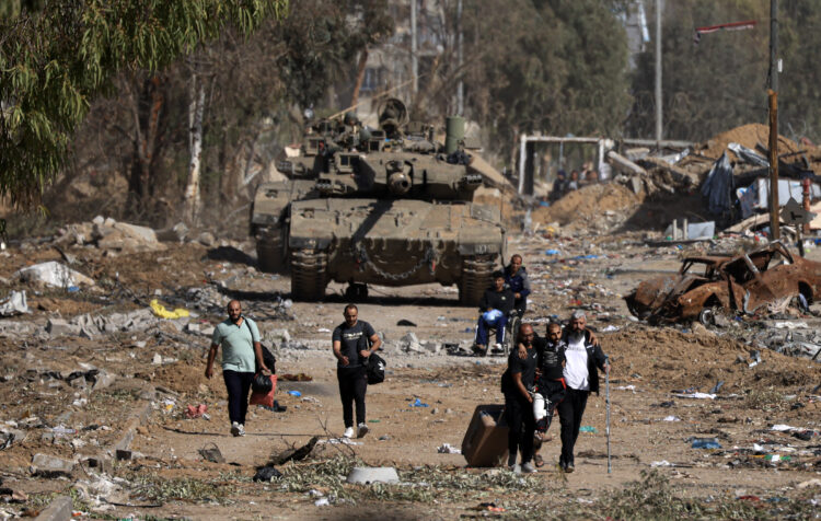 EDITORS NOTE: Graphic content / Palestinians fleeing the north through the Salaheddine road in the Zeitoun district on the southern outskirts of Gaza City, walk past Israeli army tanks on November 24, 2023, following a four-day ceasefire that began early in the morning. The truce in the Israel-Hamas war took effect at 7:00 am (0500 GMT) and appeared to be holding, under a deal that will see hostages released in exchange for Palestinian prisoners. (Photo by MAHMUD HAMS / AFP)