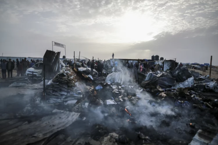 Jóvenes palestinos miran los destrozos en el campamento atacado en Rafah.