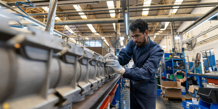 Latin american focused young man working at a manufacturing water pump factory - Industrial concepts