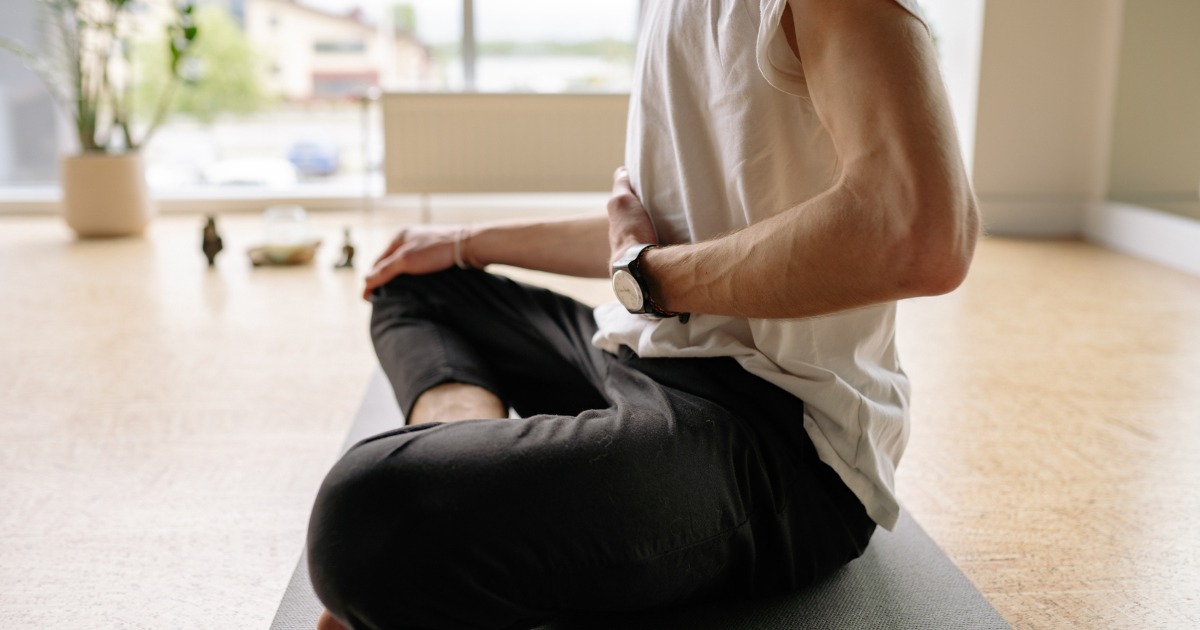 Yoga en la oficina: una herramienta esencial para reducir el estrés y aumentar el enfoque en el trabajo Persona practicando yoga, sentada y controlando la respiración.