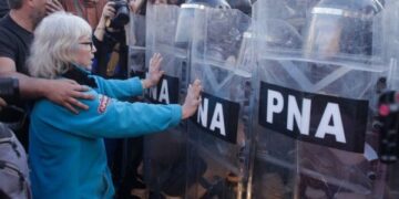 2025 cerró con 3.893 piquetes, la cifra más baja desde 2011. Mujer frente a fuerzas de seguridad.