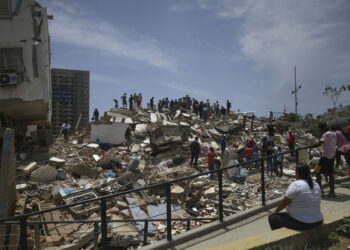 Personas son vistas sobre los escombros de un edificio derrumbado luego de que se registraran dos terremotos, en Playa Grande, estado La Guaira, Venezuela.