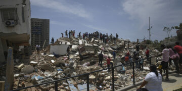 Personas son vistas sobre los escombros de un edificio derrumbado luego de que se registraran dos terremotos, en Playa Grande, estado La Guaira, Venezuela.