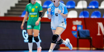 La Garrita logró su primer triunfo en el Mundial de Handball U18 An athlete in a blue and white uniform celebrates with clenched fists while another player in green watches from behind on an indoor sports court.